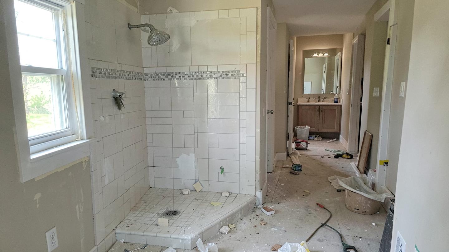 Bathroom remodel in progress with a new tile shower surround being set